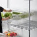 A woman using a Cambro clear plastic colander to rinse lettuce.
