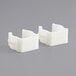 Two white plastic Lancaster Table & Seating replacement clamps.
