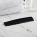 A Novo Essentials black comb on a marble surface.