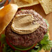 A close up of a hamburger with Pilsudski Bacon Jalapeno Mustard on it.