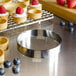 A Fat Daddio's stainless steel circular tart ring on a table with small tarts topped with raspberries.
