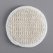 A white round Novo Essentials bath loofah with a woven surface.