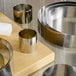 A group of Fat Daddio's stainless steel round cake molds on a metal surface.
