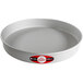 A round white metal cake pan with a red and black label.
