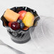 A black Cambro polycarbonate swirl bowl filled with fruit on a hospital cafeteria counter.