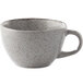 A white speckled tea cup with a handle.
