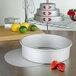 A Fat Daddio's round anodized aluminum cake pan with a removable bottom on a table with strawberries.