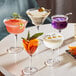 Acopa Deco martini glasses filled with a variety of colorful drinks on a table.