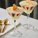 Two Acopa martini glasses filled with dessert on a table.