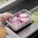 A person holding a clear plastic Vigor food pan with sliced onions.