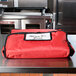 An American Metalcraft red nylon pizza delivery bag on a counter.