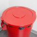 A red Continental Huskee round plastic lid on a red trash can.