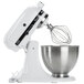 A white KitchenAid stand mixer with a wire whisk attachment.