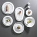 A group of white porcelain salad bowls with food on them.