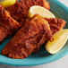 A plate of J.O. Southern Fish Fry fried fish with lemon wedges.
