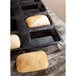 A black Sasa Demarle rectangular bread mold with 10 loaves of bread in it.