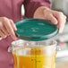 A person holding a Vigor green plastic lid over a container of liquid.