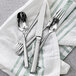 A silverware set with a Fortessa Scalini appetizer/cake fork on a table with a green towel.