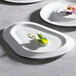 A Corona by GET Enterprises bright white porcelain platter with food on it, including a cucumber and dragon fruit.