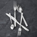 A Fortessa Catana stainless steel appetizer/cake fork on a black surface.