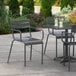 A Lancaster Table & Seating matte gray aluminum outdoor arm chair on a patio with drinks.