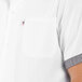 A close up of a Uncommon Chef white cook shirt with black and white checkered trims and a pocket.