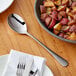 An Acopa Industry stainless steel serving spoon in a bowl of red potatoes.