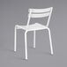 A white Lancaster Table & Seating outdoor side chair with a metal frame.