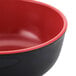 A red and black melamine bowl with a red rim.