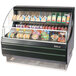 A black Turbo Air low profile horizontal air curtain display case with food and drinks on display.