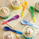 A table with cups of ice cream with sprinkles and assorted color-changing heavy weight plastic spoons.