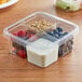 A Fabri-Kal clear plastic container with yogurt, fruit, and granola inside.