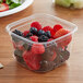 A Fabri-Kal plastic deli container of berries on a table.