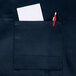 A navy blue Chef Revival bib apron with a pocket holding a pen and paper.