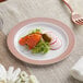 A Visions white plastic plate with a rose gold and copper lattice design holding a plate of food with salmon and radishes.