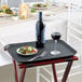 A Choice black non-skid serving tray with a bottle of wine and a salad on it.