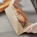 A person holding a sandwich in a Choice paper bag.