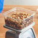 A Fabri-Kal clear PET container of nuts on a scale.