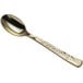 A close-up of a Visions Hammersmith gold plastic spoon with a silver spoon.