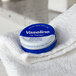 A blue and white Vaseline Lip Therapy Original tin on a white towel.
