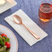 A Visions rose gold plastic spoon on a napkin.