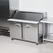A Traulsen stainless steel refrigerated sandwich prep table with silver doors.