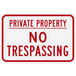 A white rectangular aluminum sign with "Private Property / No Trespassing" in red text.