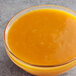 A bowl of apricot puree on a gray surface.
