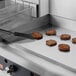 A Cooking Performance Group Ultra Series countertop griddle with a spatula cooking meat patties.