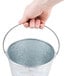 A hand holding a Tablecraft galvanized steel beverage bucket.