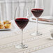 A pair of Acopa Elevation wine glasses on a table with a glass of red wine.