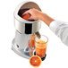 A hand squeezing an orange into a Ceado S98 electric citrus juicer.