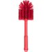 A close-up of a Carlisle red multi-purpose cleaning brush with bristles.