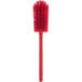 A Carlisle red bottle cleaning brush with a long handle.